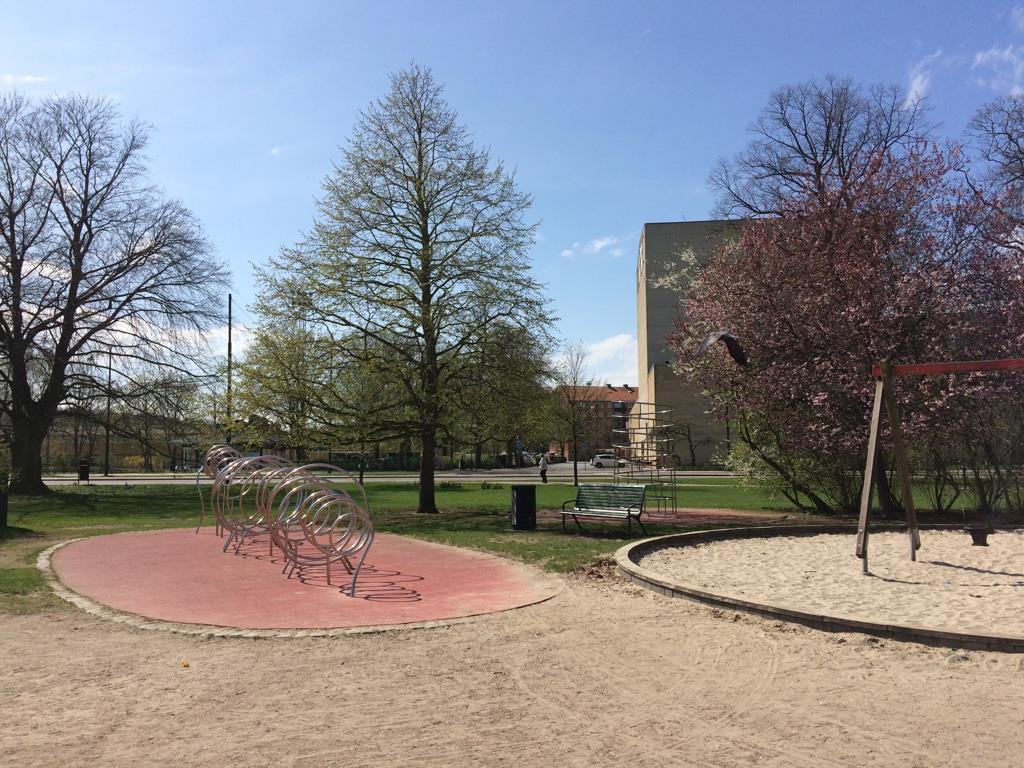 Lekplatsen upplevs som större än vad den är då det saknas fysiska gränser som ramar in den, blicken fortsätter långt ut mot den omgivande parken och vägarna runt omkring.