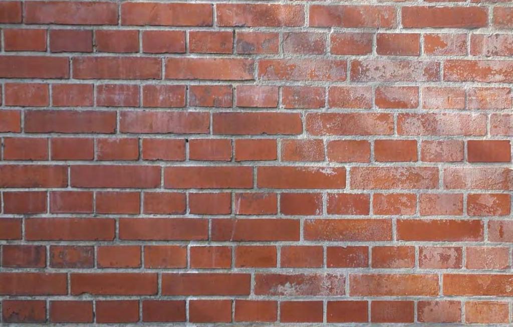 Under den gulnade stenytan syns den ursprungliga svartgråa kulören. Murparti på södrafasaden under pågående renovering 2014.