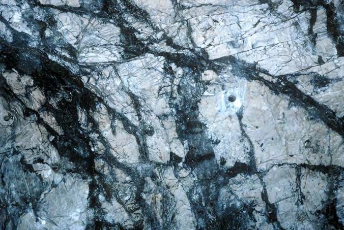 A B Figur 27. A. Nätverk av zinkblände, blyglans och svavelkis samt manganocummingtonit och tefroit i vit dolomitmarmor. Ortväggen i E malmen 811 m nivå. Bildbredd ca 2 m. B. Stuff från ortväggen i bild A.