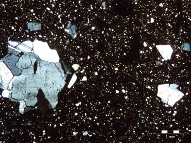Fig.15. Mikroskopfoto av tunnslip av godset i ugnsschaktfragment F61 från A707, Ledsjö. I det övre fotot i korspolariserat ljus framträder granitmagringen tydligt medan hålrummen efter växtmagringen.