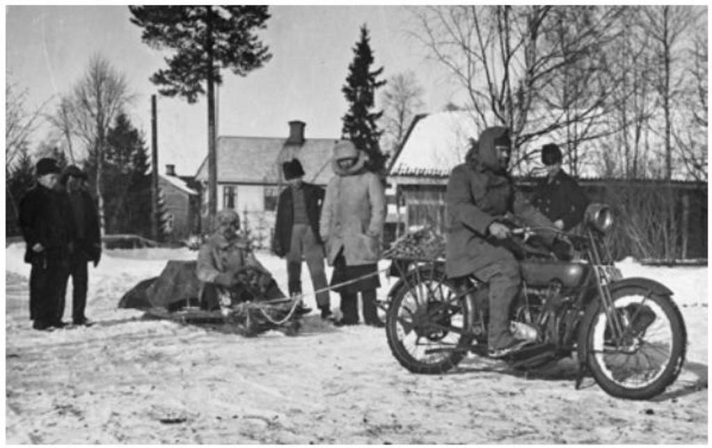 Bio-Nisse på motorcykeln med Calle Jularbo, dragspel och andra pinaler på kälken. Bio-Nisses Tältbiograf turnerade runt i Norrland från 1920-talet till 1964 och visade film.