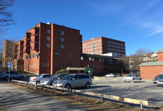 Område 3, gråblå radhus med vita knutar i träpanel uppförda i 2 våningar. I förgrunden syns även komplementbyggnader och lekplats.