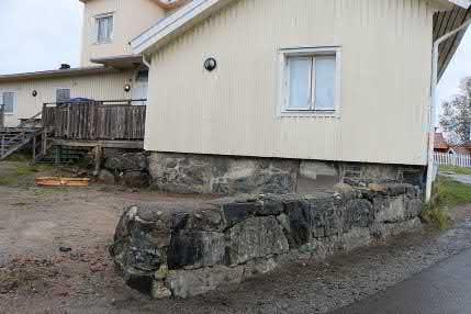 Naturstensmuren fungerar som tomtavskiljare mot Gårdavägen. Muren är en fogad skalmur som följer den omgivande terrängen som till stor del utgörs av berg.