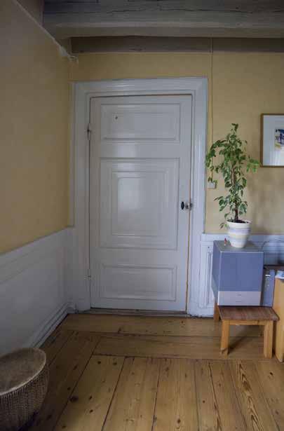 INTERIÖR MED BRÄDGOLV, PANEL OCH BJÄLKTAK FRÅN 1700-TALET. DÖRREN ÄR AV HELFRANSK TYP MED KAMMARLÅS OCH TRE FYLLNINGAR, DEN MITTERSTA FYLLNINGEN HAR RUNDADE HÖRN. FOTO.