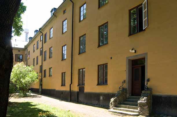 Gårdsfasaden till bebyggelsen mot Falkenbergsgatan. Hus 1 i förgrunden har en trappa med sidor av marksten samt dekorativt smidesräcke.