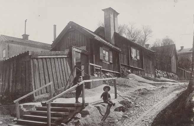SKEPPARGRÄND SÖDERUT FRÅN LOTSGATAN. DE TVÅ SKORSTENARNA DOMINERAR INTRYCKET AV FASTIGHETEN LOTSEN 20. FOTO: OKÄND FOTOGRAF OCH ÅR. E17719.