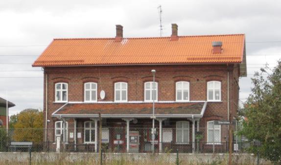 Det är en rödmålad plåtbyggnad med svart sadeltak, byggd 1988.