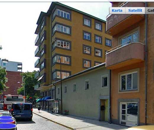 Byggnaden har en karakteristisk fasad med sina utskjutande balkonger, mörka putsomfattningar runt fönstren och sin