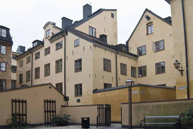 KVARTERET SETT FRÅN HÖRNET TRÄDGÅRDSGATAN / TRÄDGÅRDSTVÄRGRÄND, DÄR EN MUR RINGAR IN GÅRDEN MED DEN TIDIGARE BRUNNEN, PYGMALION 1. DET FYRA VÅNINGAR HÖGA HUSET BEVARAR EN HISSBOM MOT GÅRDEN.